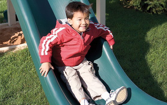 boy going down playset slide in winter weather boy on playset during the winter