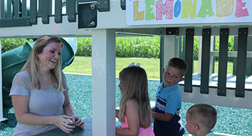 mom and kids playing outside at a pretend lemonade stand mom and kids playing outside